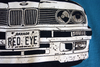 Closeup of shirt design. The front of the BMW E30 shows chips and imperfections from daily driving. The license plate reads "RED EYE".